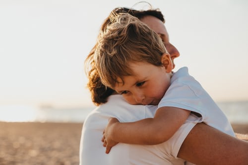 little-boy-in-white-shirt-cuddling-mother-over-shoulder-smiling