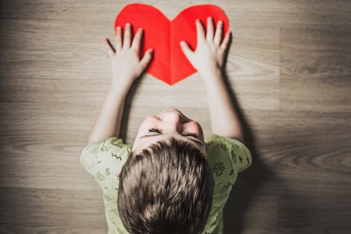 Child touching a paper heart