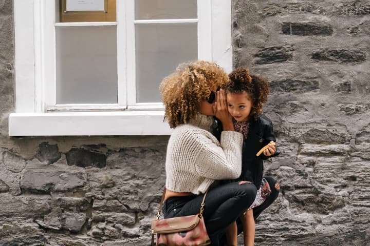 Mum whispering into her daughter's ear